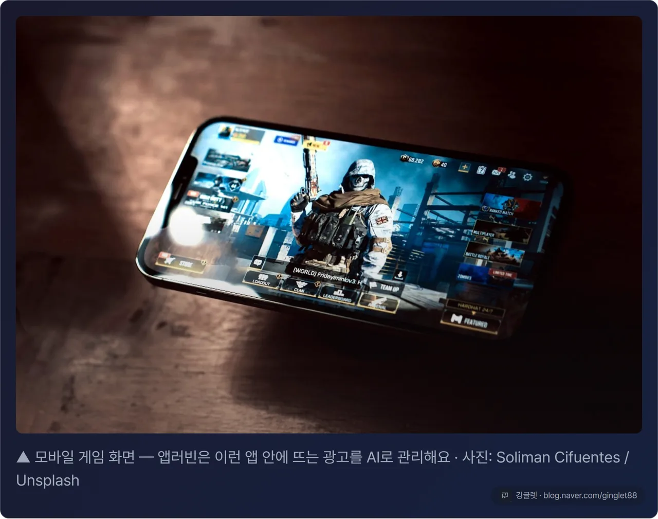 모바일 게임 화면 위에 광고 배너가 뜬 스마트폰을 든 손 (스톡) — 앱러빈이 파는 ’앱 안 광고’를 보여주는 분위기 컷, 다크 카드 + 출처 캡션